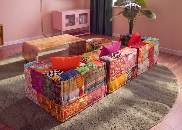 Canapea modulară patchwork colorată, aranjată &icirc;n jurul unei măsuțe de cafea din lemn, pe un covor rotund, &icirc;ntr-un living contemporan.